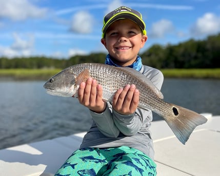kid on boat holding small redfish