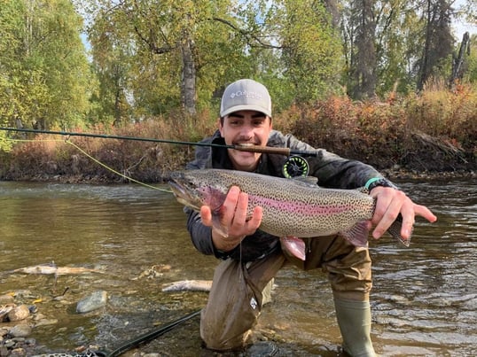 Man Holding Rainbow Trout on a River in Alaska