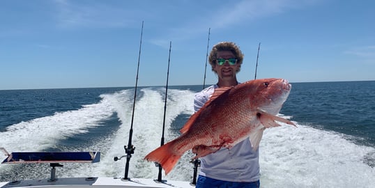 man holding up red snapper on back of boat in gulf