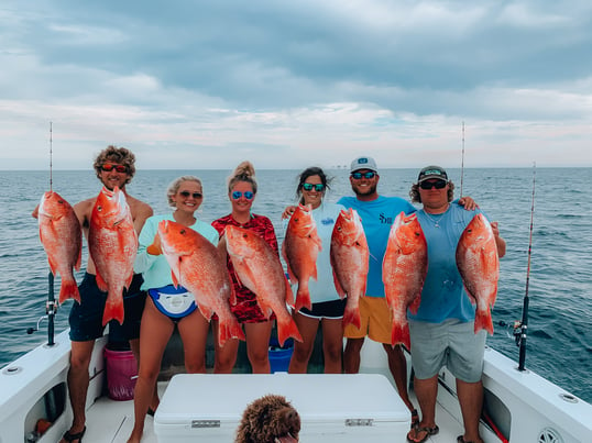 Group of people fishing holding up red snappers