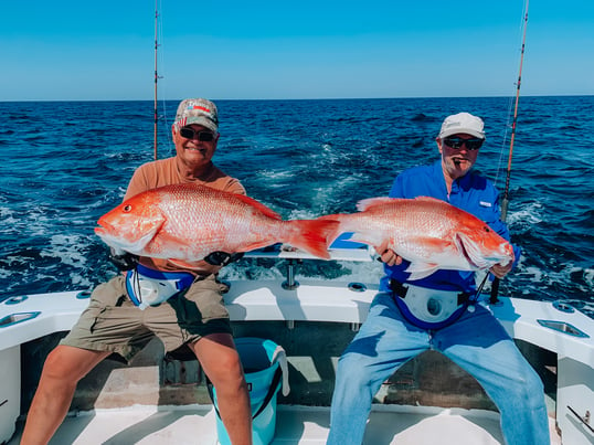 two old men holding up big red snapper