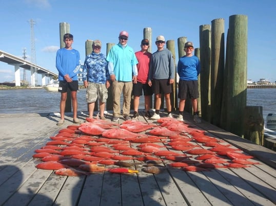 group standing with tons of red snapper on the dock